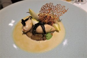 מנת גורמה בצלחת כוללת שני פריטים ממולאים בציפוי אצות, מונחים על פטריות מוקפצות. הוא מעוטר באנדיב וסריג עדין ופריך, מוקף ברוטב שמנת.