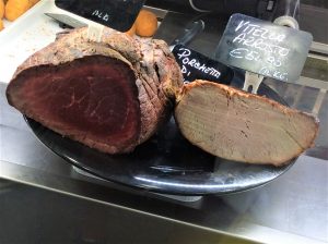 תצוגה של שני סוגי בשרים על מגש שחור. הנתח השמאלי כהה ונראה לא מבושל, ואילו הימני הוא צלי בהיר פרוס. תגי המחיר מעל כל אחד מציינים 35.90 אירו לק