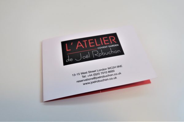 חוברת עבור L'Atelier de Joël Robuchon, Covent Garden. הוא כולל פרטים ליצירת קשר: 13-15 West Street, London WC2H 9NE, טלפון +44 (0)20 7010 8600, דוא
